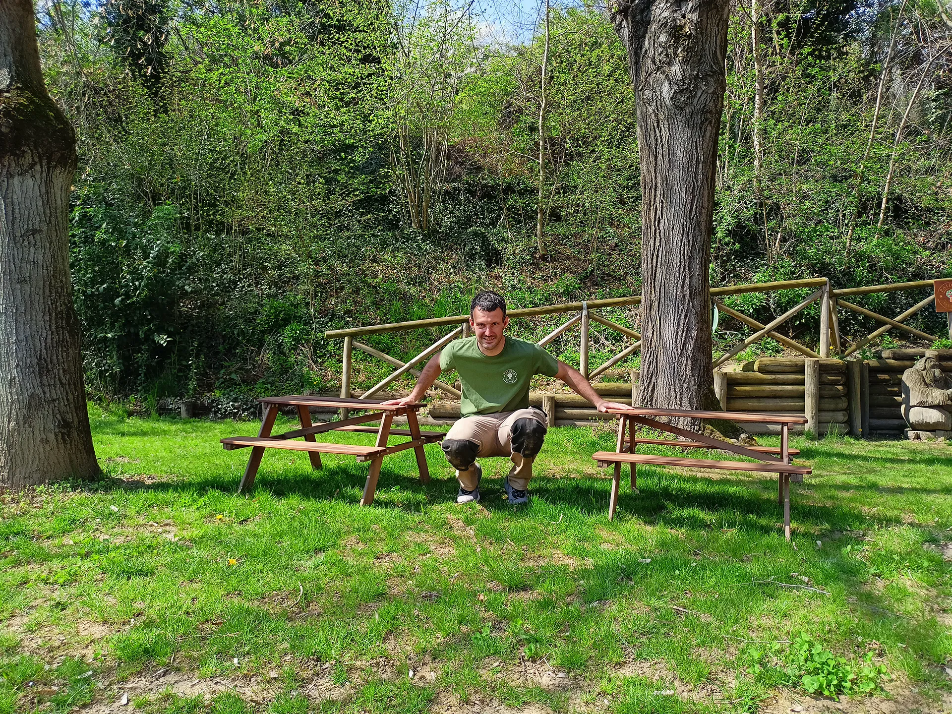 un uomo appoggiato a una panchina di legno in mezzo al prato