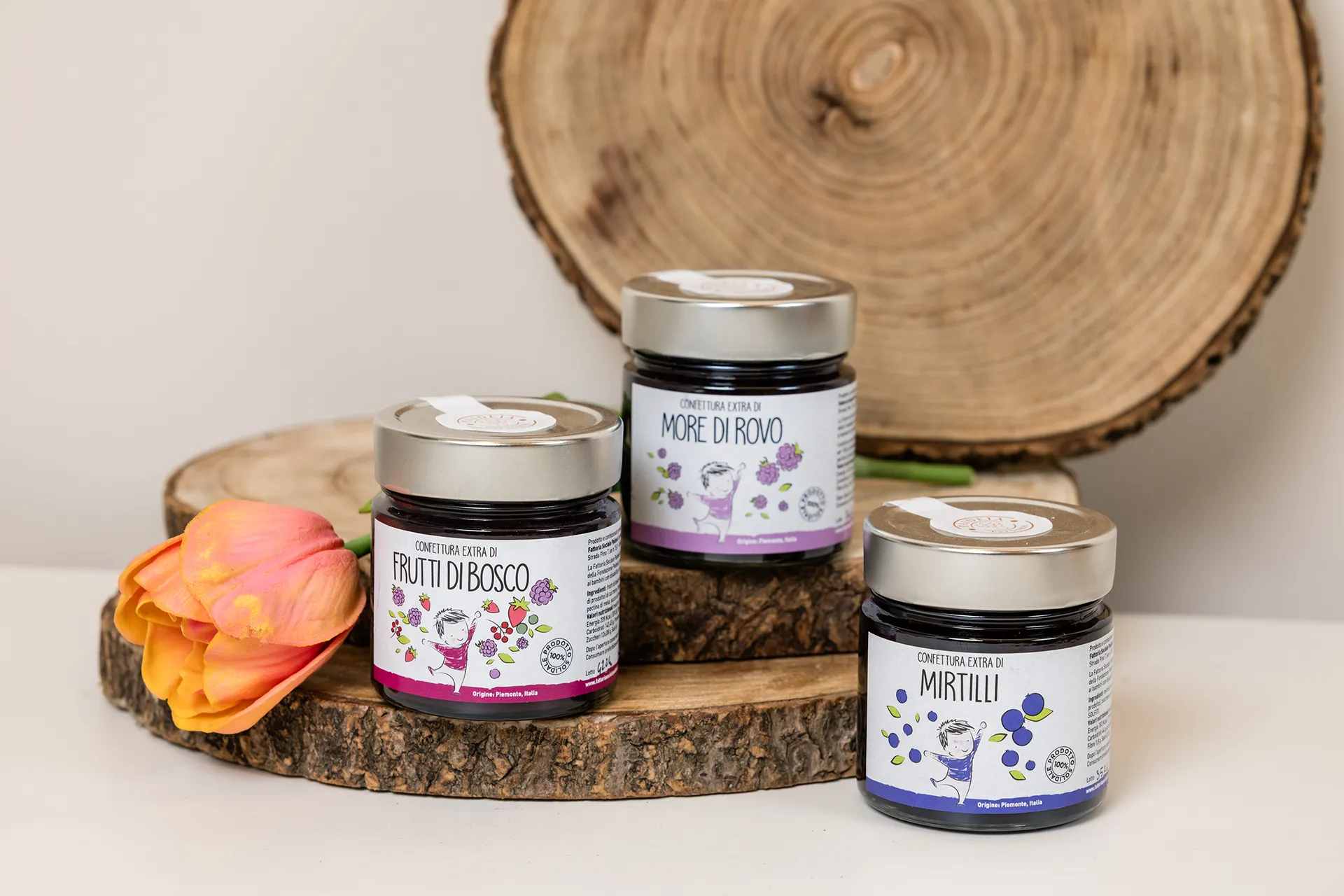 3 vasetti di confetture diverse appoggiate su un supporto di legno
